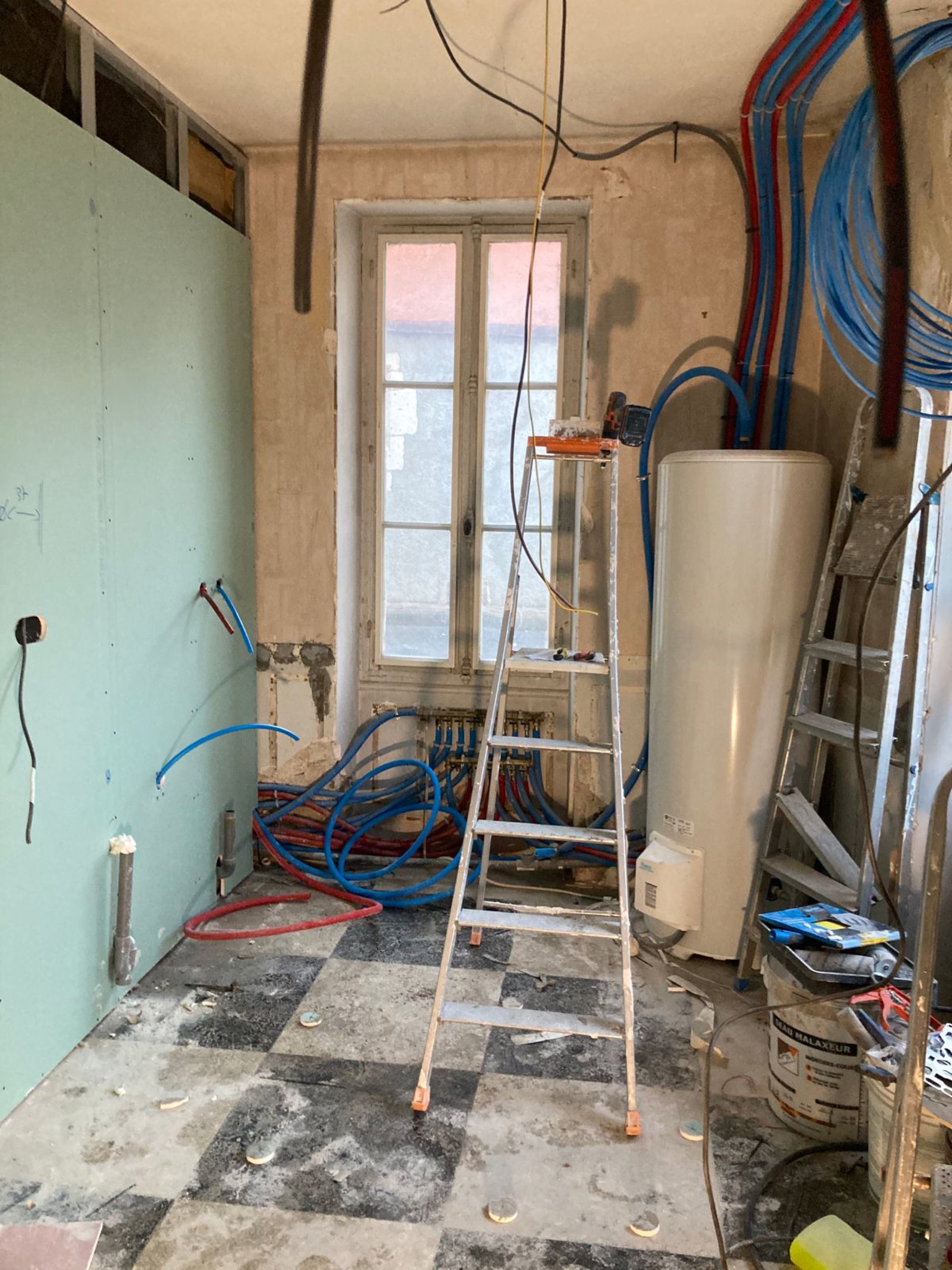 Buanderie en travaux, tuyaux apparents et chauffe-eau